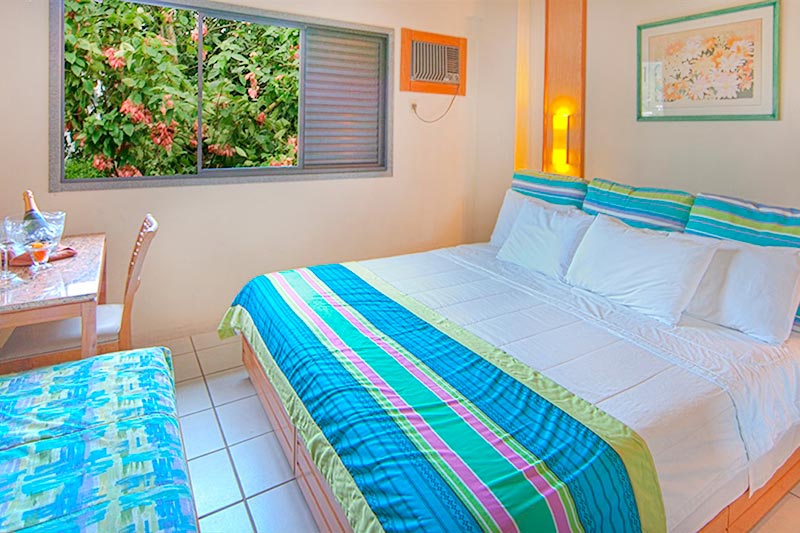 Quarto Standard vista para resort contendo uma cama casal , sofá e mesa para refeições